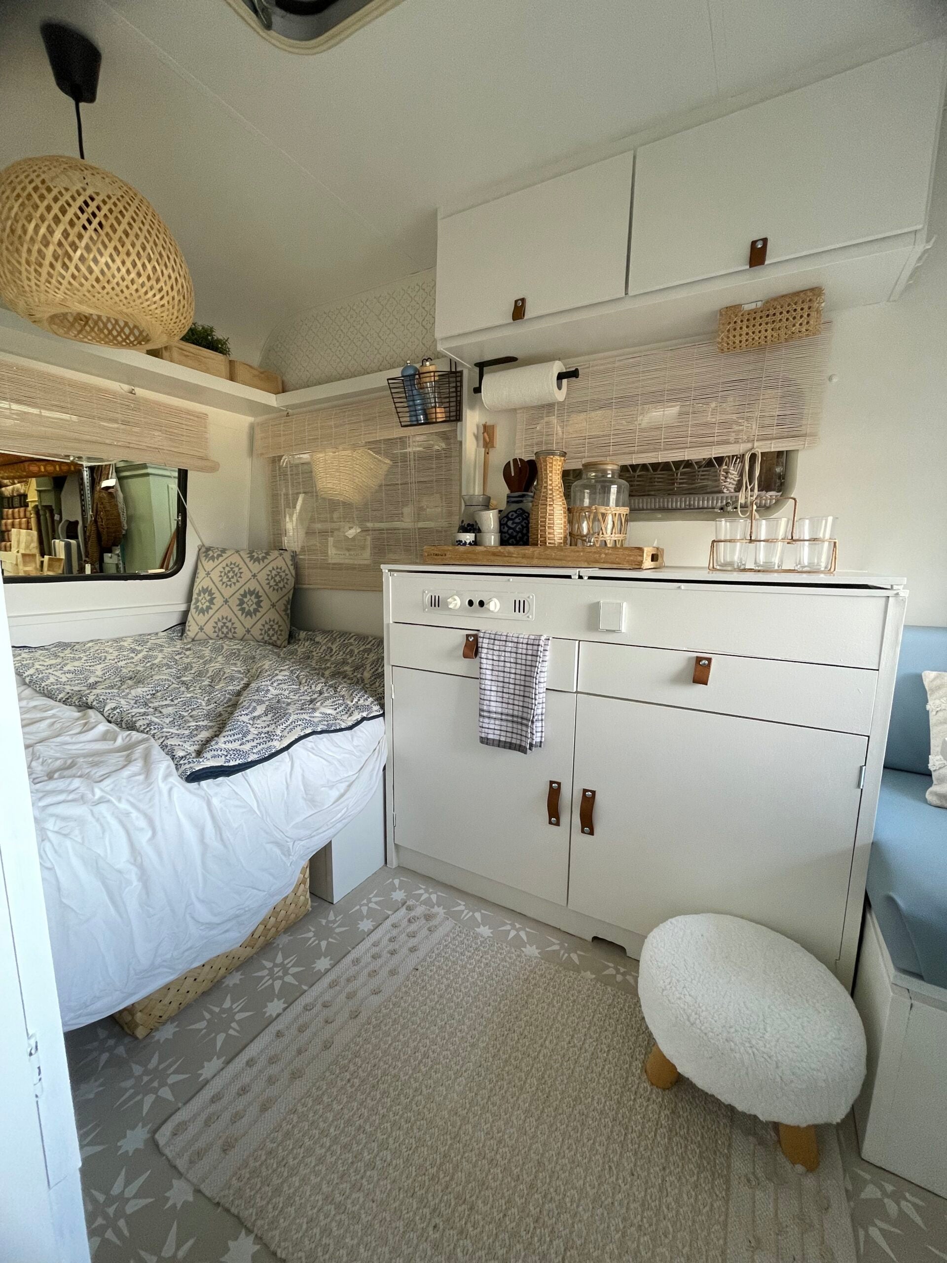 Stylish interior of the Adria 305 caravan featuring a cozy bed, modern kitchen area, and decorative elements.