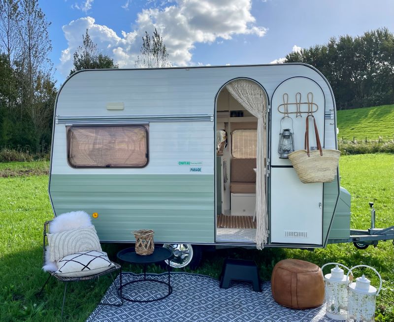 Chateau 320 caravan parked on green grass, featuring a cozy entrance, decorative lanterns, and outdoor seating.