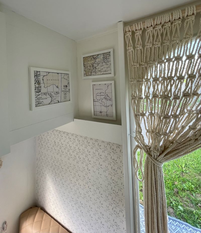 Chateau 320 interior featuring framed maps, a textured curtain, and a cozy seating area in a caravan setting.