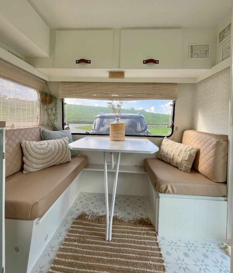 Cozy interior of the Chateau 320 caravan featuring beige seating, a white table, and natural light.